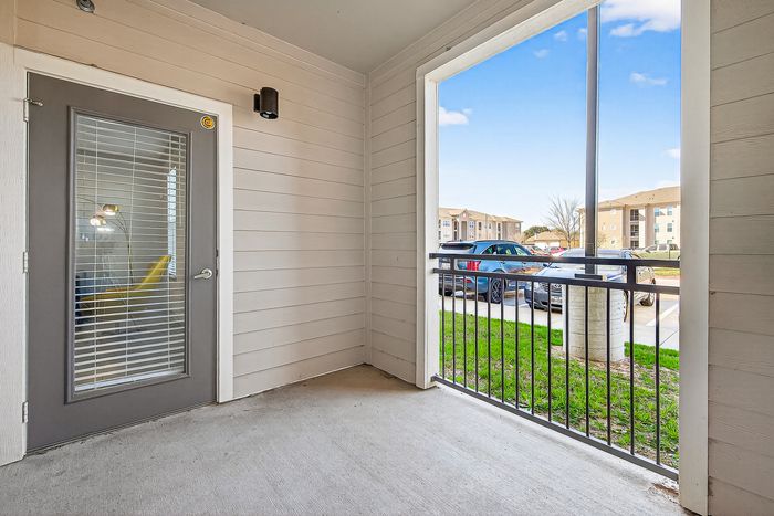 Inviting apartment patio with a view of neatly parked cars and expansive blue sky, offering a tranquil outdoor experience.