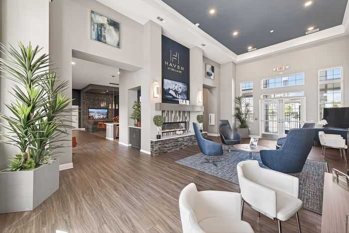 Elegant apartment lobby featuring modern decor, plush seating areas, and large windows allowing natural light to flood the open spaces.