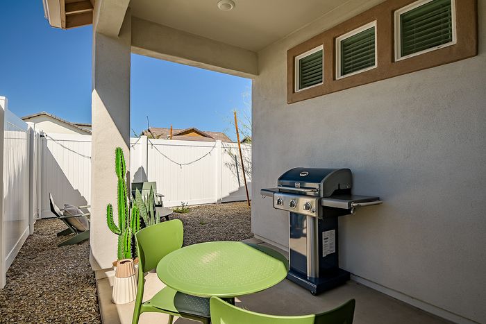 Charming outdoor patio with modern grill and seating, perfect for relaxing and entertaining.