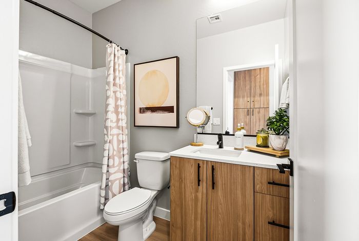 Modern bathroom featuring sleek wooden cabinetry, stylish shower curtain, and decorative wall art with a serene aesthetic.