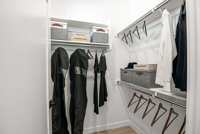 Spacious and stylish walk-in closet with elegant shelving, modern storage boxes, and ample hanging space.