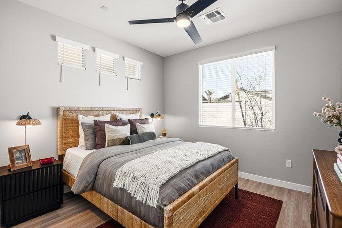 Bright and cozy bedroom featuring a stylishly textured bedframe, elegant bedside lamps, and a sunlit window offering a serene view.