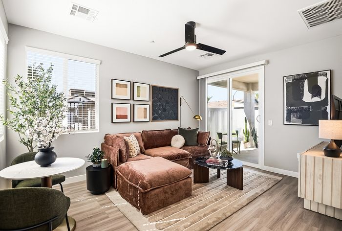 Chic living room with plush brown sectional sofa, modern decor, and ample natural light from large windows and sliding glass doors.
