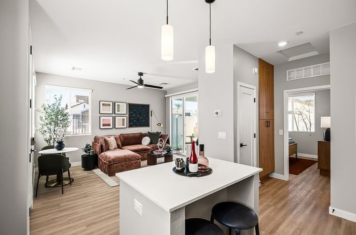 Modern apartment interior with open-plan living room and kitchen, featuring chic decor, cozy seating, and abundant natural light.