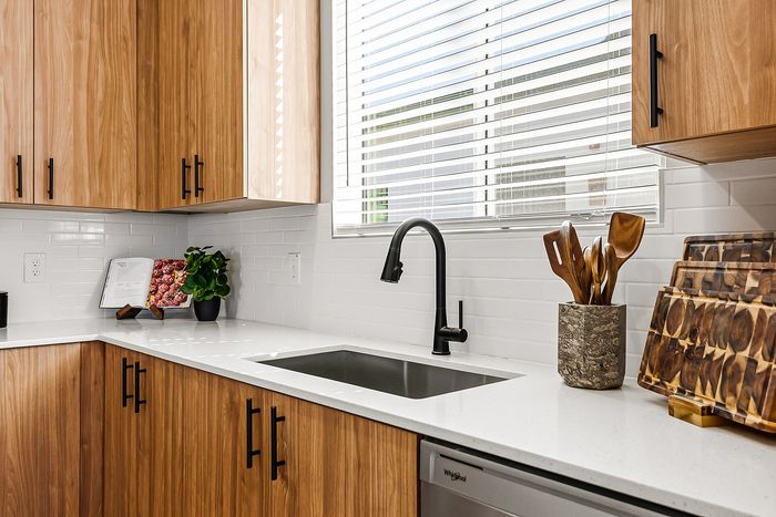 Modern kitchen with sleek wooden cabinets, elegant black fixtures, and a sunlit work surface, ideal for culinary creativity.