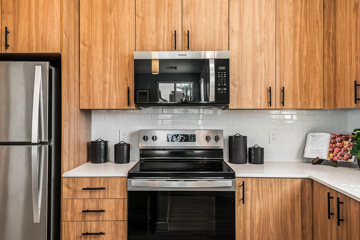 Modern kitchen with sleek stainless steel appliances, warm wooden cabinetry, and glossy white subway tile backsplash, creating a stylish and inviting cooking space.