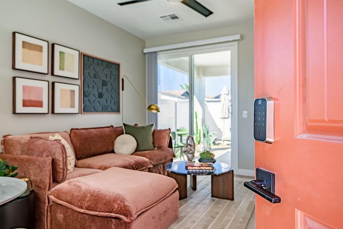 Inviting living room entrance with plush brown sectional, artistic wall decor, and abundant natural light through sliding glass doors.
