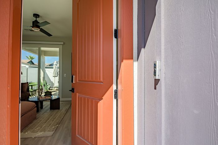 Inviting entryway with a vibrant orange door opening into a cozy living room, highlighted by modern decor and abundant natural light.