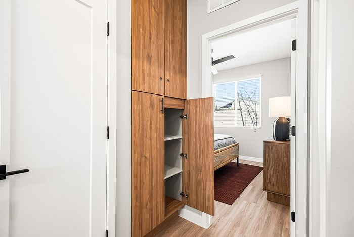 Bright and inviting bedroom entrance showcasing elegant wooden cabinetry, modern decor, and ample natural light.