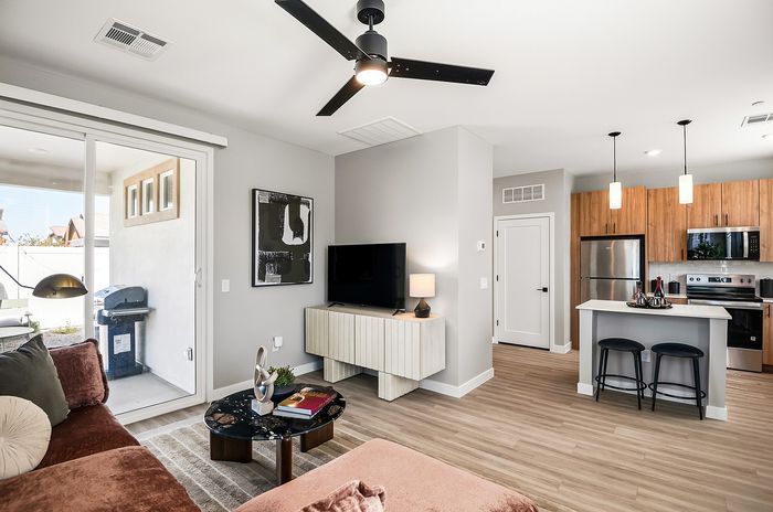 Modern open-concept living area with cozy seating, stylish decor, and a sleek kitchen with stainless steel appliances.