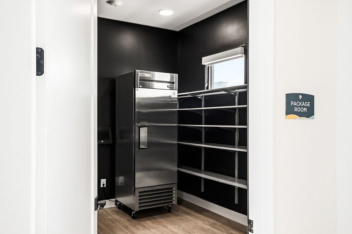 Modern package room with sleek shelving and a premium stainless steel appliance, designed for efficiency and style.