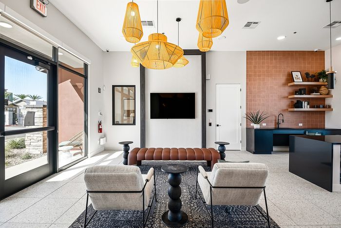 Modern lounge with chic decor features plush seating, statement pendant lights, and a sleek kitchen perfect for entertaining.
