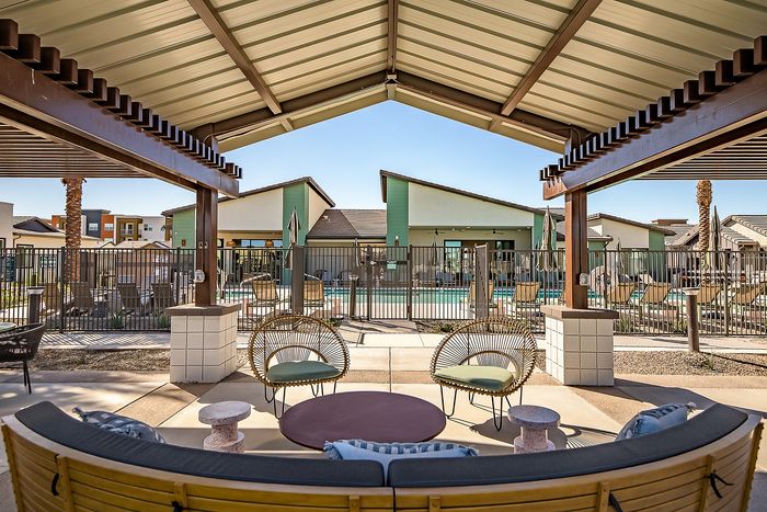 Chic outdoor patio with stylish seating overlooking a modern swimming pool in a vibrant apartment complex.