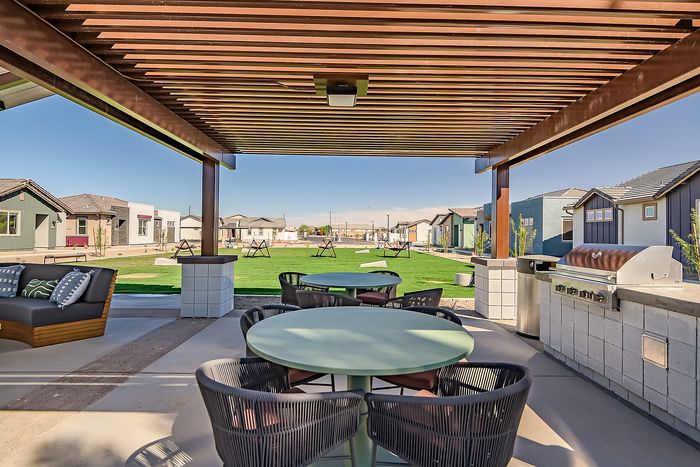 Inviting outdoor patio with modern seating and grill area, featuring lush green lawn surrounded by stylish homes.