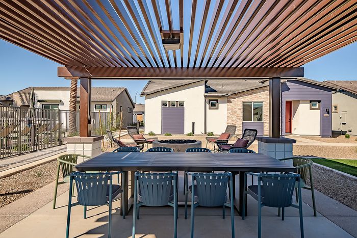 Chic outdoor patio area with modern seating under a stylish pergola, showcasing a cozy fire pit and elegant apartment exterior.