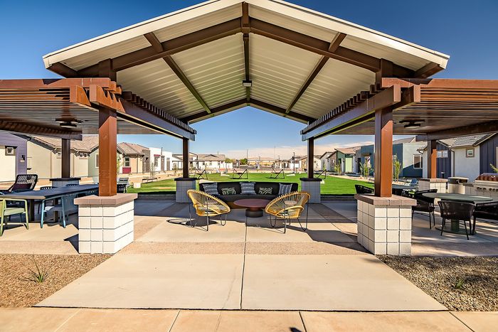 Chic outdoor patio with modern seating under a stylish pergola, offering a vibrant community space surrounded by lush green lawns.