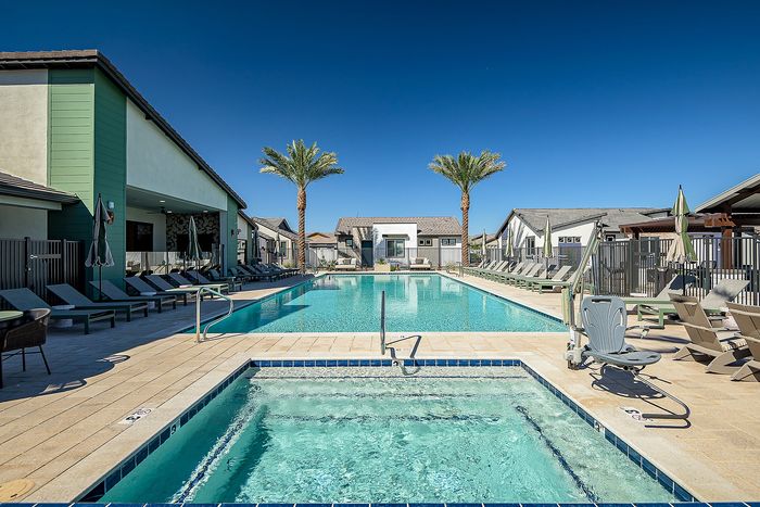 Luxurious residential pool area with inviting loungers, pristine blue water, and elegant palm trees, perfect for relaxation and leisure in a sunny climate.