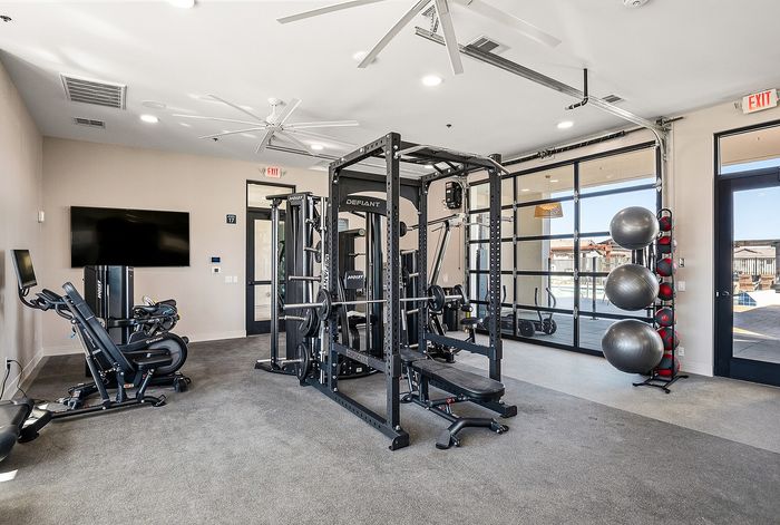 Modern fitness center equipped with state-of-the-art exercise machines, free weights, and large windows offering pool views.