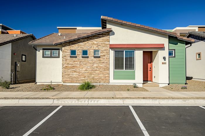 Charming modern house with colorful exterior, combining brick and vibrant green siding, set against a clear blue sky.
