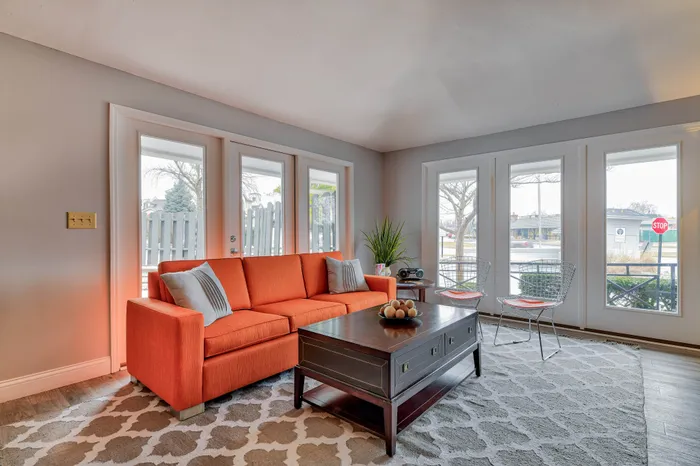 Bright and stylish living room featuring a vibrant orange sofa, elegant coffee table, and large windows for natural light.