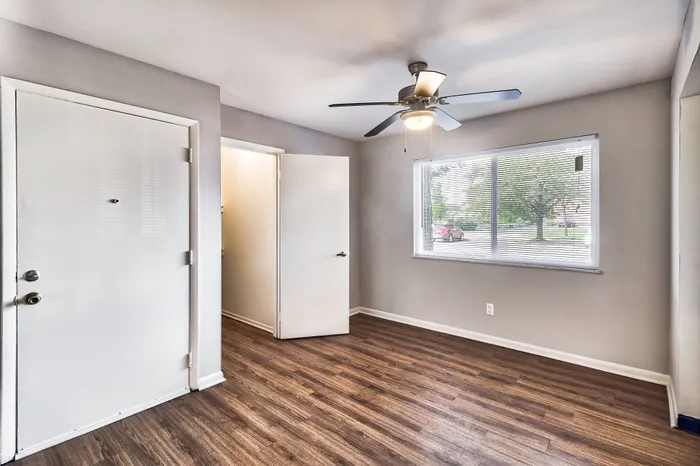 Inviting entryway with sleek wooden flooring and abundant natural light through a large window, complemented by a ceiling fan for comfort.