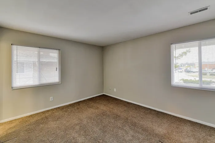 Bright and spacious room with large windows offering ample natural light and plush carpeting.