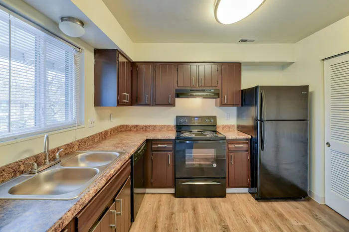 Chic kitchen with rich wood cabinetry, modern appliances, and expansive counter space under natural light.