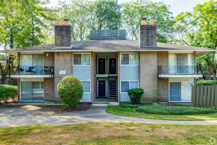 Charming two-story apartment building with spacious balconies and lush green surroundings.