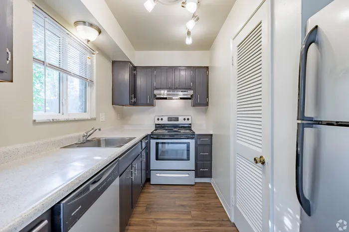 Modern kitchen with sleek cabinets, elegant countertops, and stainless steel appliances, illuminated by stylish ceiling lights.