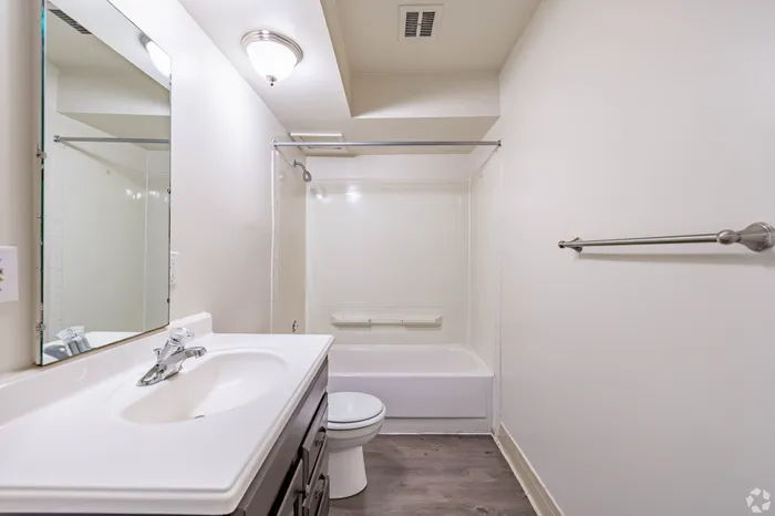 Modern bathroom featuring sleek fixtures, a spacious vanity, and a pristine bathtub with light, inviting decor.