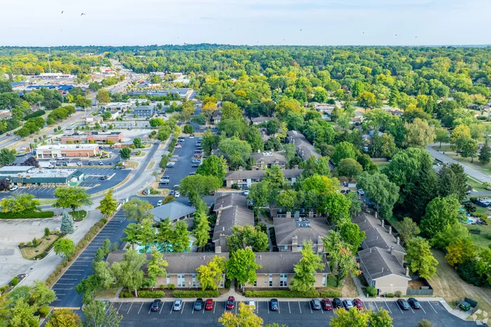 Stunning aerial view of a vibrant apartment complex surrounded by lush greenery and ample parking, offering a serene and convenient lifestyle.