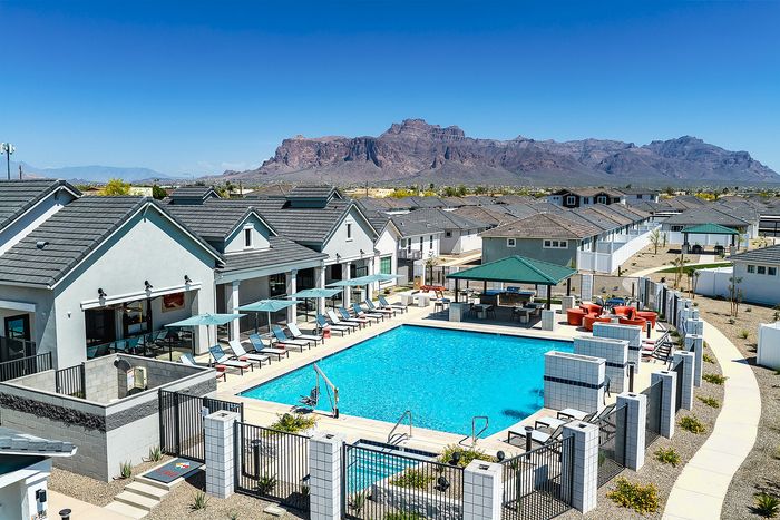 Luxurious community pool area with modern lounge chairs and umbrellas, surrounded by picturesque mountain views and elegant homes.
