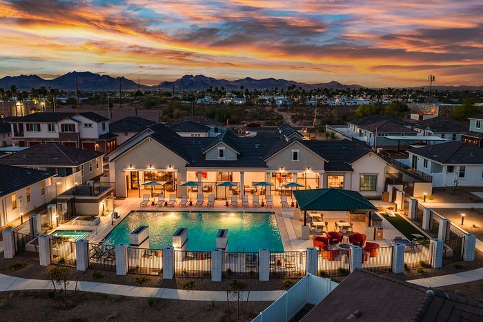 Luxury apartment complex featuring a dazzling pool and outdoor seating against a vibrant sunset backdrop, offering stunning mountain views.