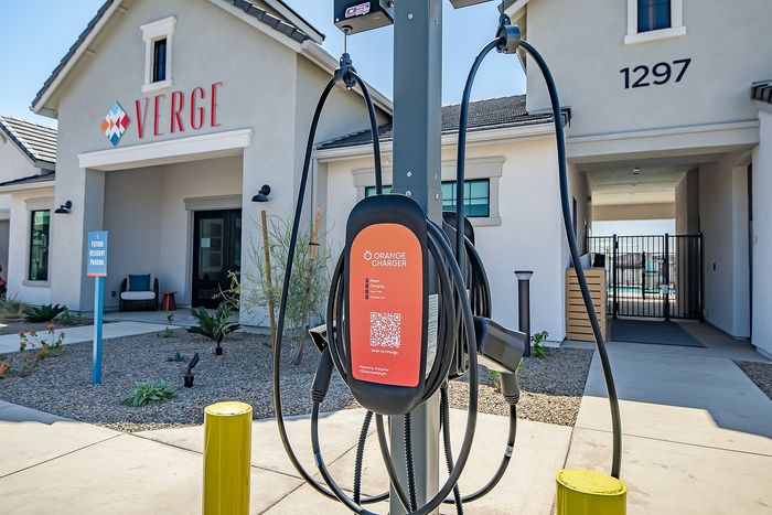 Modern apartment complex entrance featuring a convenient electric vehicle charging station, inviting future residents.