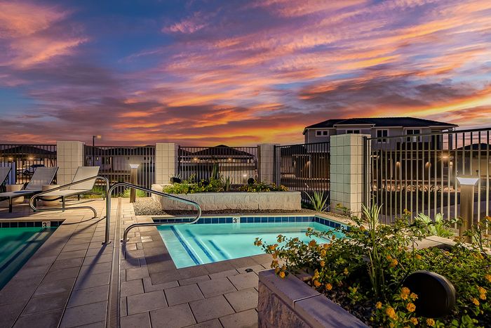 Enchanting sunset view over a luxurious pool and relaxation area, framed by lush greenery and elegant tiles.