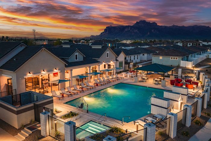 Elegant apartment complex showcasing a luxurious outdoor pool area with stylish lounge chairs and vibrant sunset views, perfect for relaxation and social gatherings.