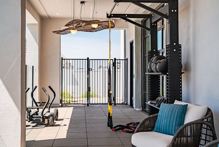 Modern home gym space with elegant lighting, exercise equipment, and comfortable seating, perfect for fitness enthusiasts.