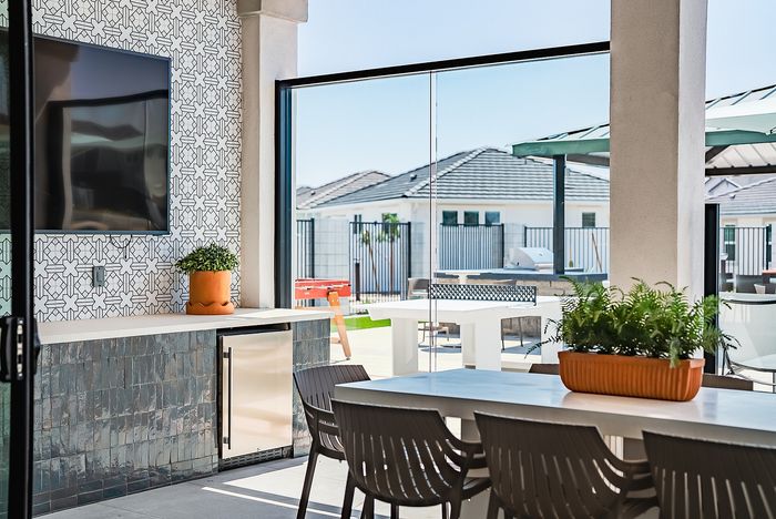 Chic outdoor living area featuring modern dining furniture, stylish tiled wall, and lush greenery, perfect for relaxation and entertaining.