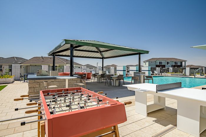 Chic outdoor recreational area featuring a sparkling pool, shaded patio with seating, and engaging games like foosball and ping pong.