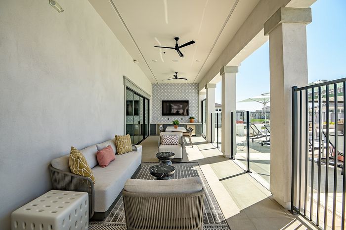 Inviting outdoor lounge with plush sofas, modern decor, and a sleek ceiling fan, perfect for relaxed entertaining.