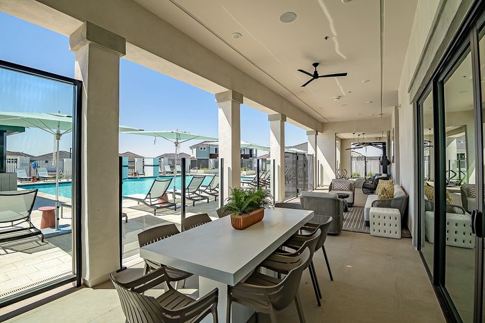 Luxurious outdoor patio with modern seating and lush poolside view, perfect for relaxation and entertaining.