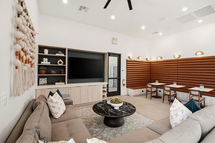 Modern lounge area featuring cozy seating with stylish pillows, contemporary wall decor, and a sleek entertainment center, perfect for relaxation and gatherings.