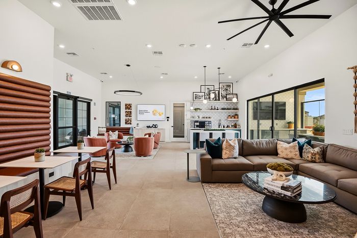 Luxurious open-concept living area with modern decor, featuring a spacious sectional sofa, elegant dining setup, and stylish kitchen in a bright, well-lit space.