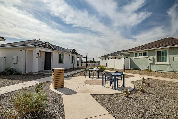 Charming outdoor space with modern bungalow and stylish seating area under a vast sky, perfect for relaxation.