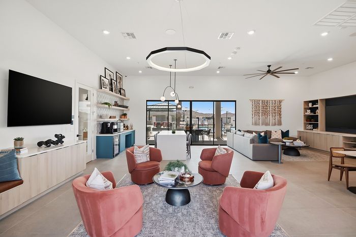 Luxurious modern living room with elegant decor, featuring plush pink chairs, large TV, stylish lighting, and expansive patio view.