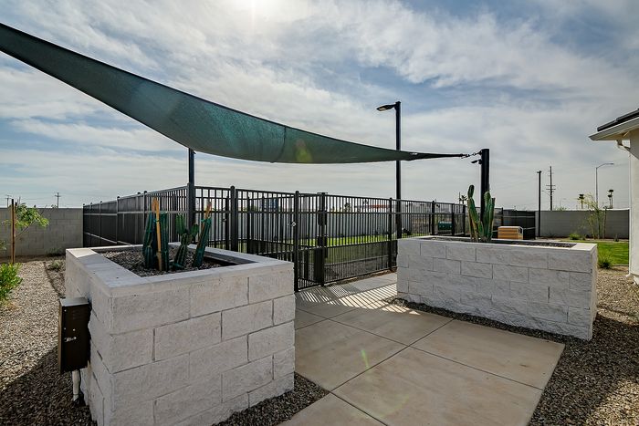 Inviting outdoor area with a modern sunshade, stylish stone planters, and lush green space, perfect for relaxation and entertainment.