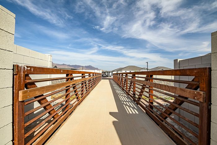 Inviting walkway with wooden railings leading to modern apartments under a vibrant blue sky.