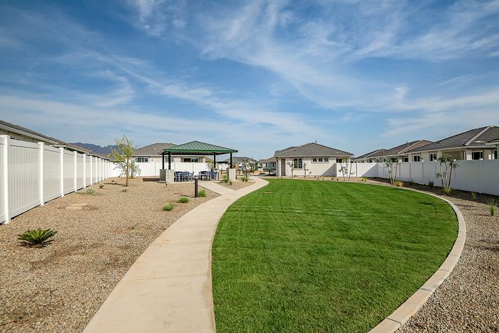 Charming residential area with a lush green lawn, modern gazebo, and beautiful outdoor seating, perfect for relaxation and gatherings.