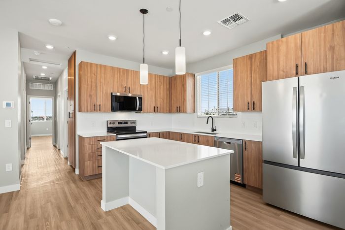 Modern kitchen with sleek stainless steel appliances, elegant pendant lighting, and warm wood cabinetry, offering a welcoming and functional space.
