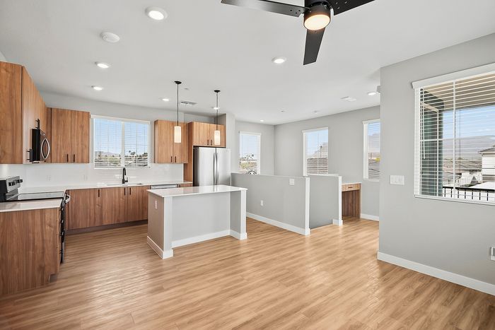Chic open-plan kitchen and living area with modern wood cabinetry, sleek appliances, and abundant natural light illuminating the stylish space.